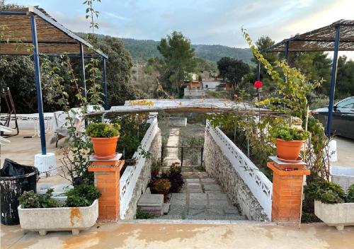 uma ponte de pedra com vasos de plantas num jardim em Habitaciones en casa rural particular La Casita em Ibi