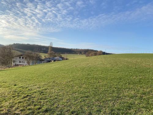 a large field of grass with a house in the background at Pension Am Hohberghof in Dielheim