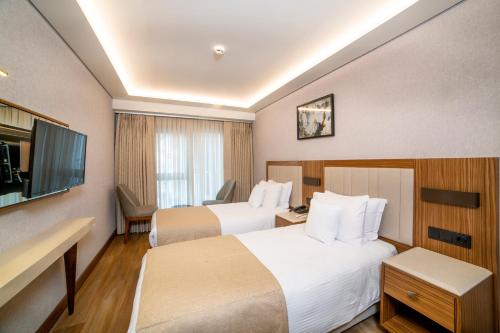 a hotel room with two beds and a flat screen tv at Erboy Hotel Istanbul Sirkeci in Istanbul