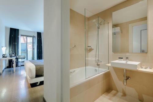 a white bath tub sitting next to a white sink at RAMBLAS HOTEL powered by Vincci Hoteles in Barcelona