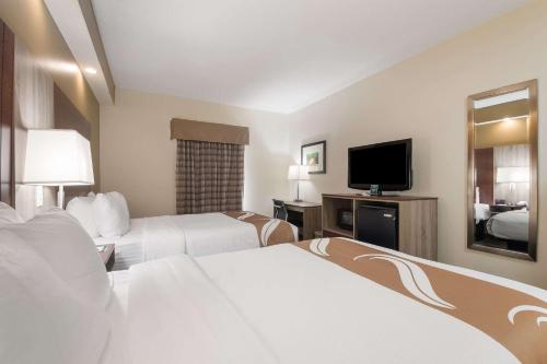 a hotel room with two beds and a flat screen tv at Quality Inn Alcoa Knoxville in Alcoa