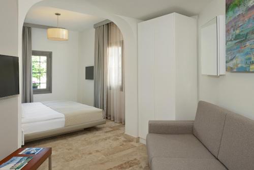 Habitación de hotel con cama y sofá en Yalikavak Marina Garden Hotel en Yalıkavak