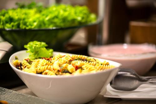 a bowl of pasta on a table with a salad at Erboy Hotel Istanbul Sirkeci in Istanbul