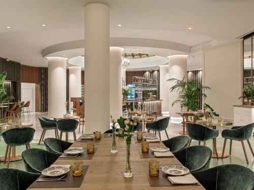 a dining room with a long table and green chairs at Hotel Colón Gran Meliá - The Leading Hotels of the World in Seville