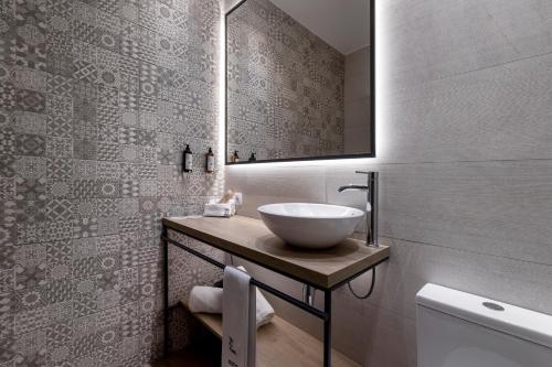 a bathroom with a sink and a mirror at Petit Palace Plaza de la Reina in Valencia