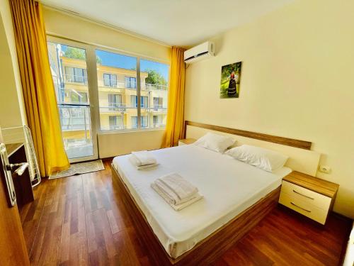a bedroom with a bed with white sheets and a window at Solei Apartments in Primorsko