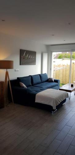 a living room with a blue couch and a bed at Maison moderne plein coeur de Ouistreham in Ouistreham