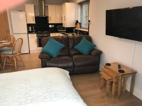 a living room with a leather couch and a table at Cozy lodge with private garden and bbq in Barton-upon-Humber