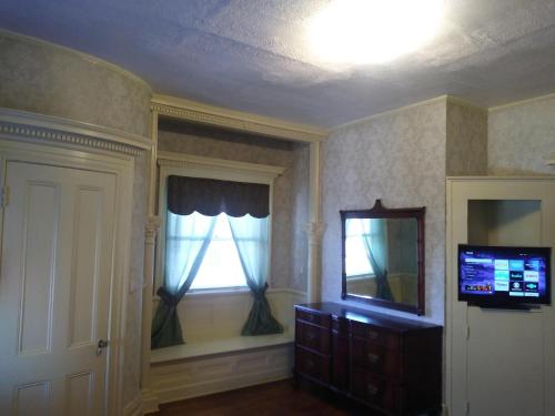 a living room with a television and a window at Mini Mansion Hotel near public transportation is the yellow and green house on the corner of 8th st and Madison avenue in Plainfield