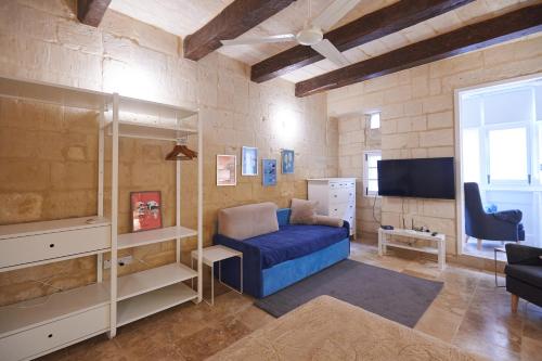 Casa San Carlo في فاليتا: غرفة معيشة مع أريكة زرقاء وتلفزيون