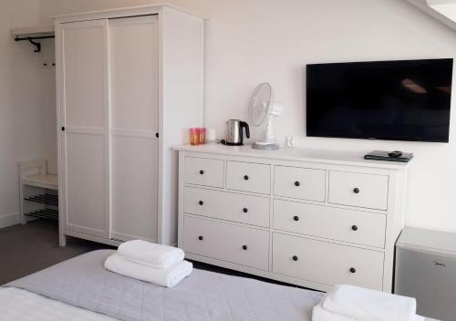 a white bedroom with a tv and a white dresser at Avila Park & SPA in Dziwnówek
