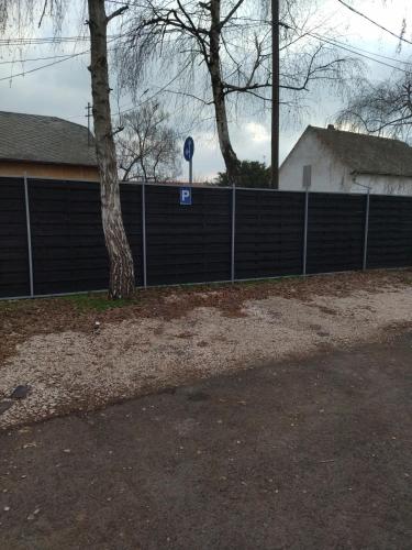 a fence with a tree in front of a house at Valentin Apartman in Makó