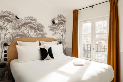 Un dormitorio con una cama con almohadas blancas y una ventana en My Maison In Paris Montmartre, en París
