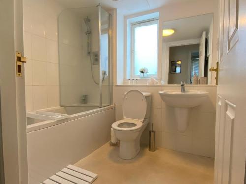 Baño blanco con aseo y lavamanos en Maltings Apartment - Spacious 2 Bed Ground Floor Apartment, en Kirkcaldy