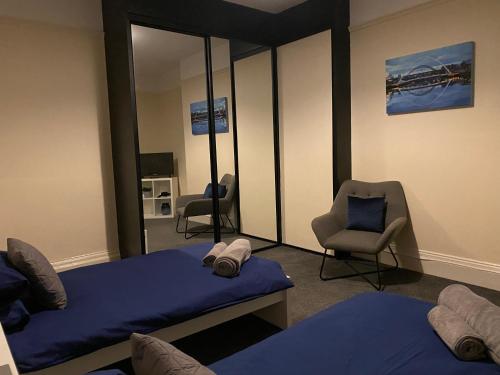 Habitación con 2 camas, silla y espejo. en Town centre stay Northumberland FREE WIFI AND CLOSE TO BEACH en Blyth