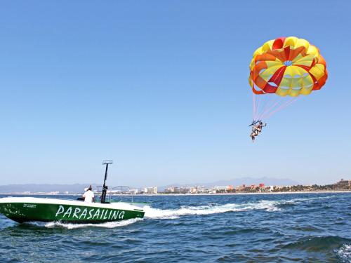 a man in a green boat in the water with a parachute at Paradise Village in Nuevo Vallarta 