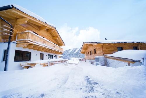 a snow covered road in front of a log cabin at Almdorf Auszeit Fageralm in Forstau