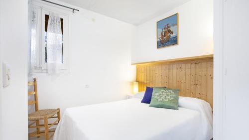 a bedroom with a white bed and a chair at Clip H-3 - Llafranc in Llafranc
