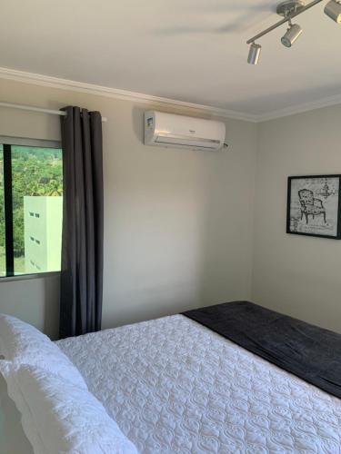 ein Schlafzimmer mit einem weißen Bett und einem Fenster in der Unterkunft Excelente Apartamento Vista Mar em Maragogi in Maragogi