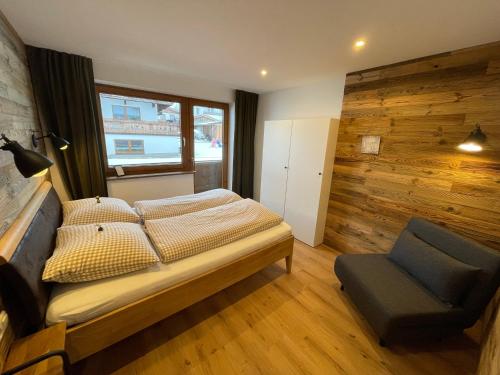 - une chambre avec un lit et une chaise dans l'établissement Landhaus Zillertal, à Ramsau im Zillertal