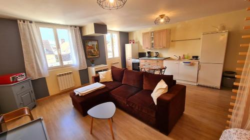 ein Wohnzimmer mit einem braunen Sofa und einer Küche in der Unterkunft Le Studio Bis - Appartement meublé tout confort Centre Ville in Pont-Sainte-Maxence