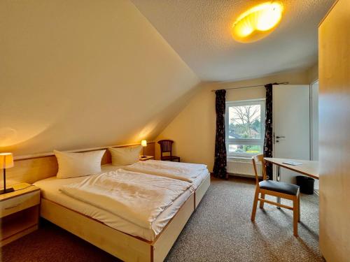 Schlafzimmer mit einem Bett, einem Schreibtisch und einem Fenster in der Unterkunft Gästehaus Südheide in Hambühren