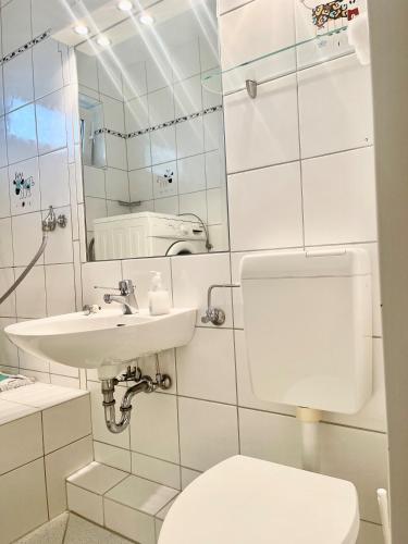 a white bathroom with a toilet and a sink at Ruhiges Landhaus am Wald mit Garten mit Schlafzimmer und Schlafnische in Aurich
