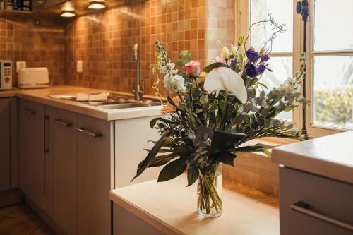 un vase de fleurs assis sur une table dans une cuisine dans l'établissement Villa avec vue - Piscine privée, cuisine d'été, jeux vidéo et appareils de fitness, à Puygaillard