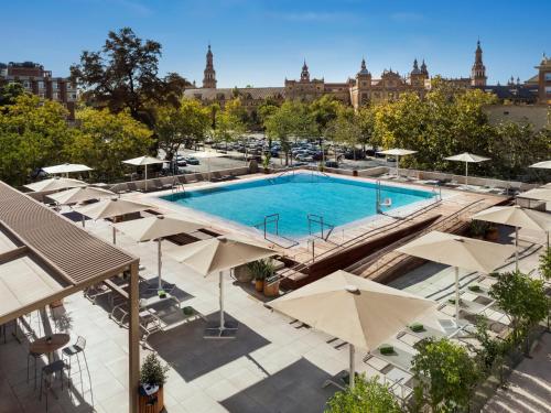Una vista aérea de una piscina con sombrillas. en Melia Sevilla, en Sevilla