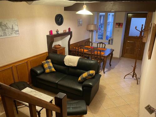 a living room with a leather couch and a table at A la petite maison de village in Sabarat