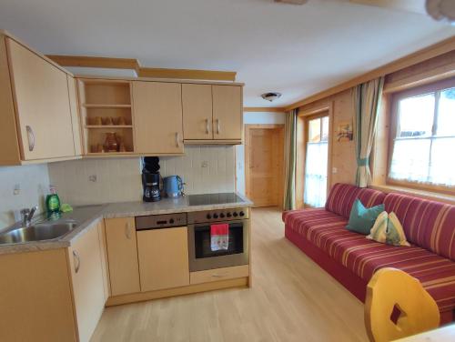 a kitchen and a living room with a red couch at Veitenhof in Krimml