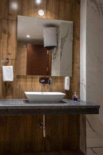 a bathroom with a white sink and a mirror at Perch Service Apartment-MG Road in Gurgaon