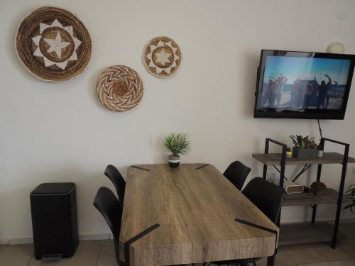 a dining room table with chairs and a tv on a wall at Lev Eilat Suites in Eilat