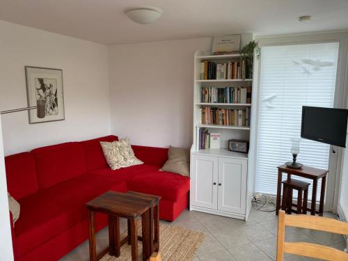 a living room with a red couch and a book shelf at Haus Perthen in Berggiesshübel