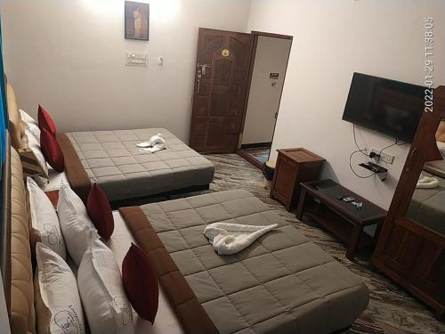 a hotel room with two beds and a television at VILLA DE SRIVAARI RESIDENCY in Puducherry