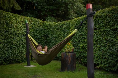 a woman is sitting in a hammock at Apartmány Adršpach " U Kozárů " in Adršpach