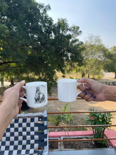 two people holding coffee cups on a bench at Suman Madhu Mansion in Nānodra