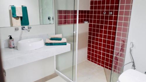 uma casa de banho com um chuveiro, um lavatório e azulejos vermelhos em Amplo e confortável. Ar condic, WiFi, TV. Metrô. Tijuca. no Rio de Janeiro