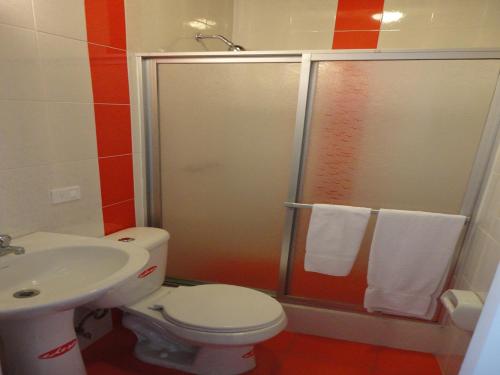 a bathroom with a shower and a toilet and a sink at Hotel Rincón Escandinavo in Quito