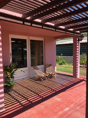 a patio with a pergola and two chairs on it at Casa rosa - se reserva con seña in Barra del Chuy