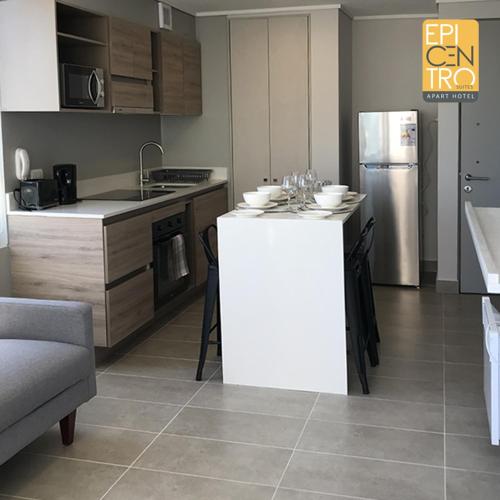 a kitchen with a white counter and a refrigerator at Epicentro Suites Apart Hotel - Temuco in Temuco
