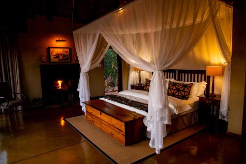 1 dormitorio con cama con dosel y chimenea en Nungubane Game Lodge, en Reserva de Welgevonden