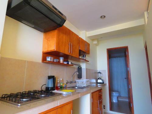 a kitchen with wooden cabinets and a stove top oven at Boulevard 251 Riverside Apartments in Iquitos