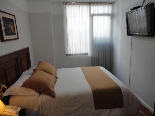 a bedroom with a bed and a window and a television at Hotel Rincón Escandinavo in Quito