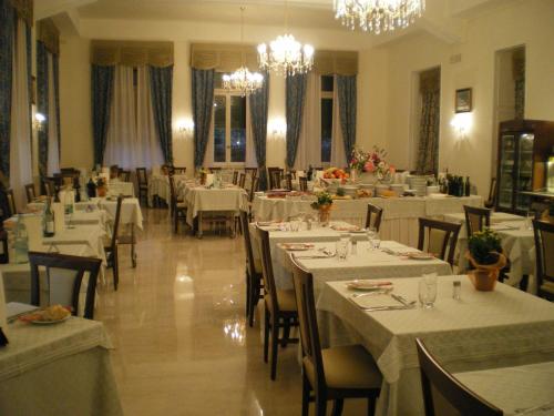 a restaurant with white tables and chairs and chandeliers at Hotel Valentini in Salsomaggiore Terme