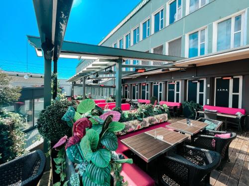 um pátio exterior com mesas, cadeiras e plantas em Magic Hotel Xhibition em Bergen