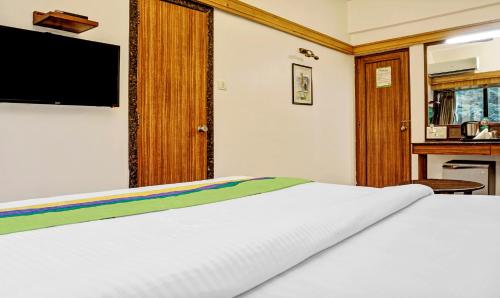 a bedroom with a bed with a television on the wall at Treebo Sahara Shivaji Nagar in Pune