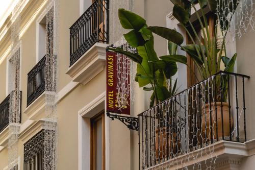 a building with a balcony and a plant on it at Hotel Gravina 51 in Seville