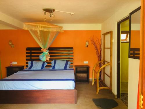 a bedroom with a bed with an orange wall at orchid villa in Ella
