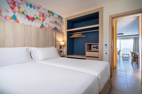 a bedroom with a large white bed and a dining room at Allegro Isora in Puerto de Santiago